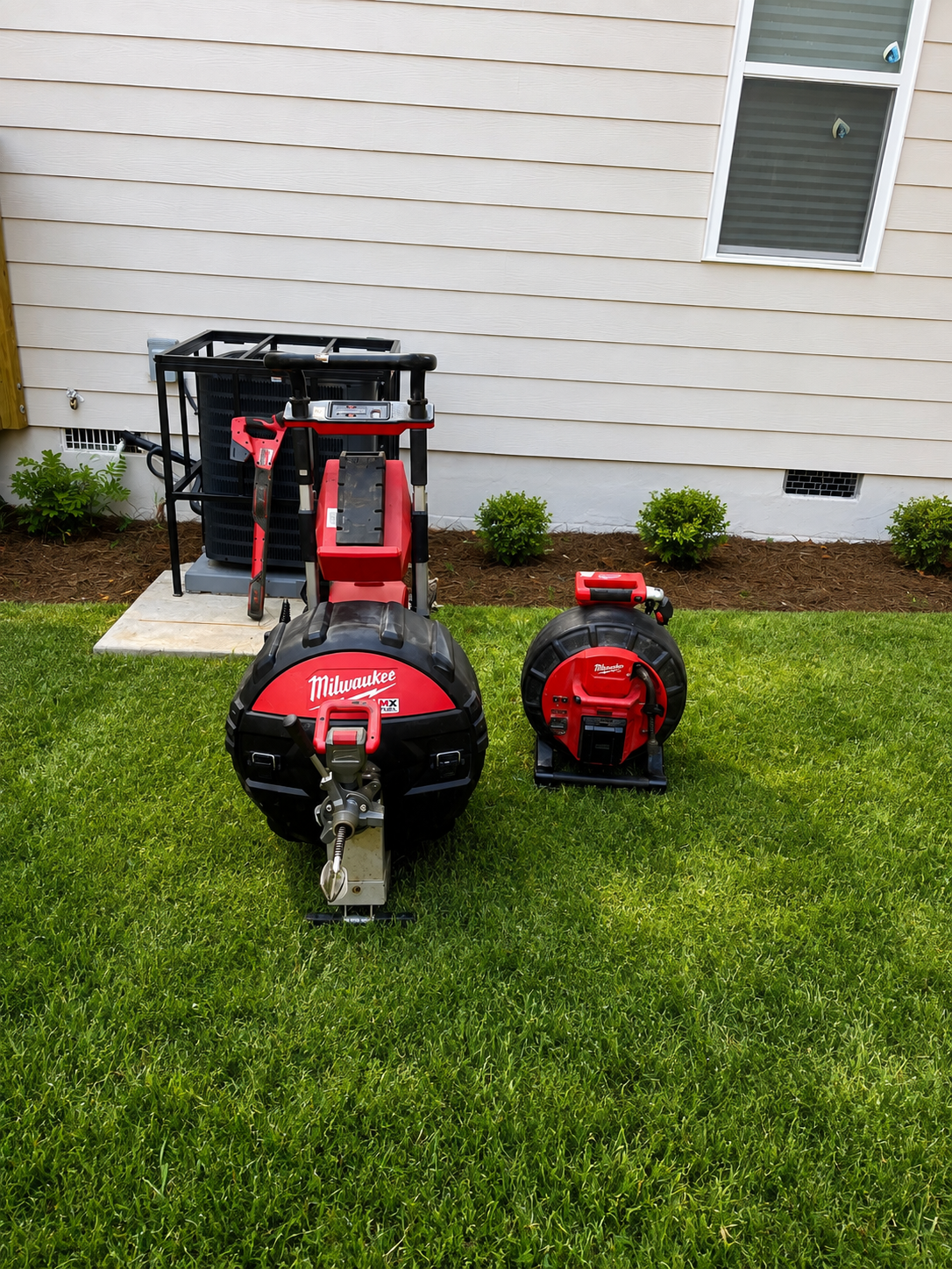Professional Milwaukee drain-cleaning machine and sewer camera reel staged outside an Atlanta-area home